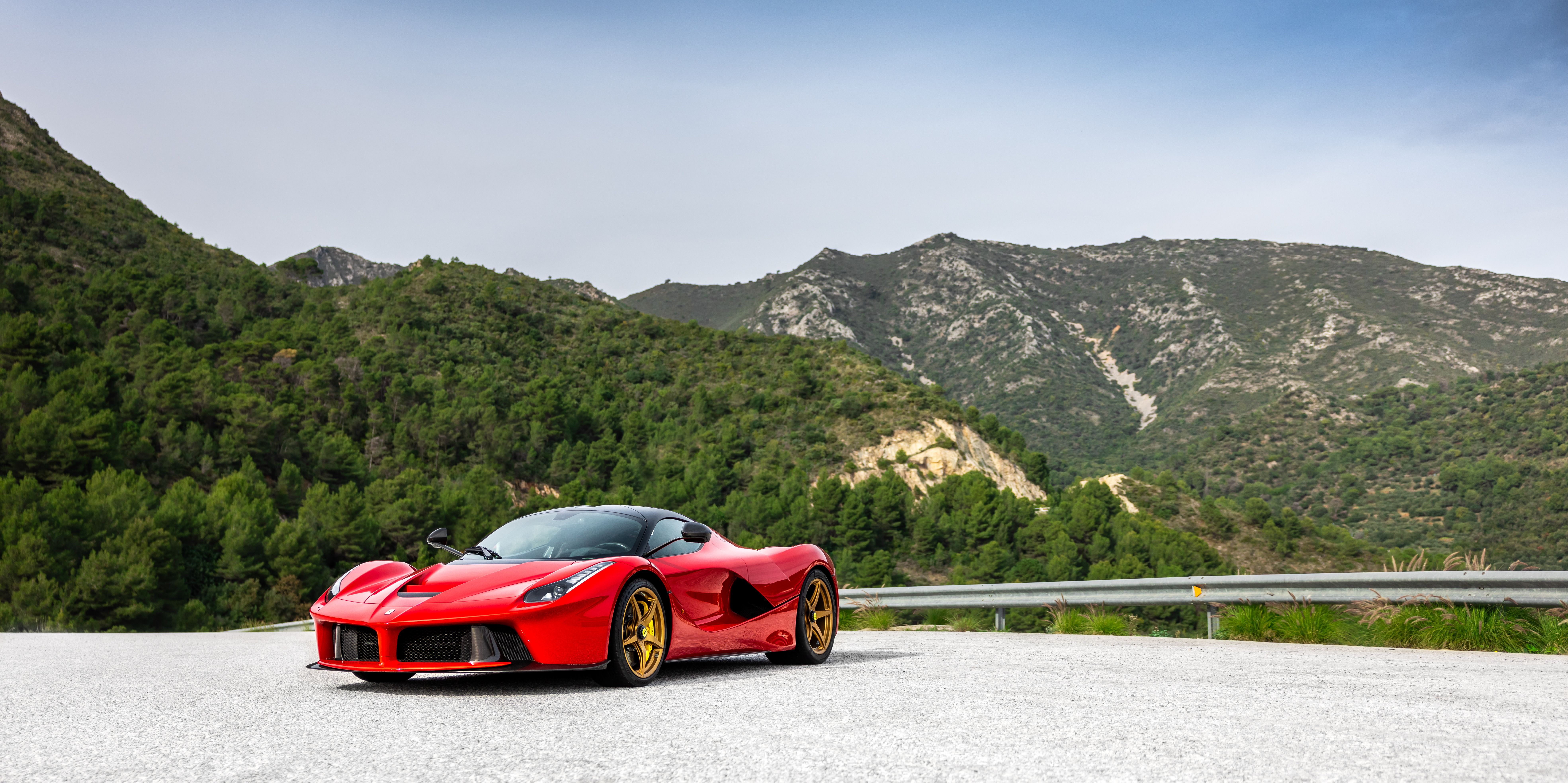 Red Ferrari LaFerrari on a mountain road above a village